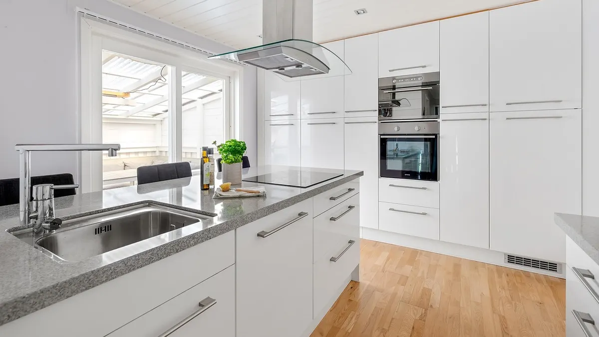 Cozinha branca moderna com bancada de granito e piso de madeira