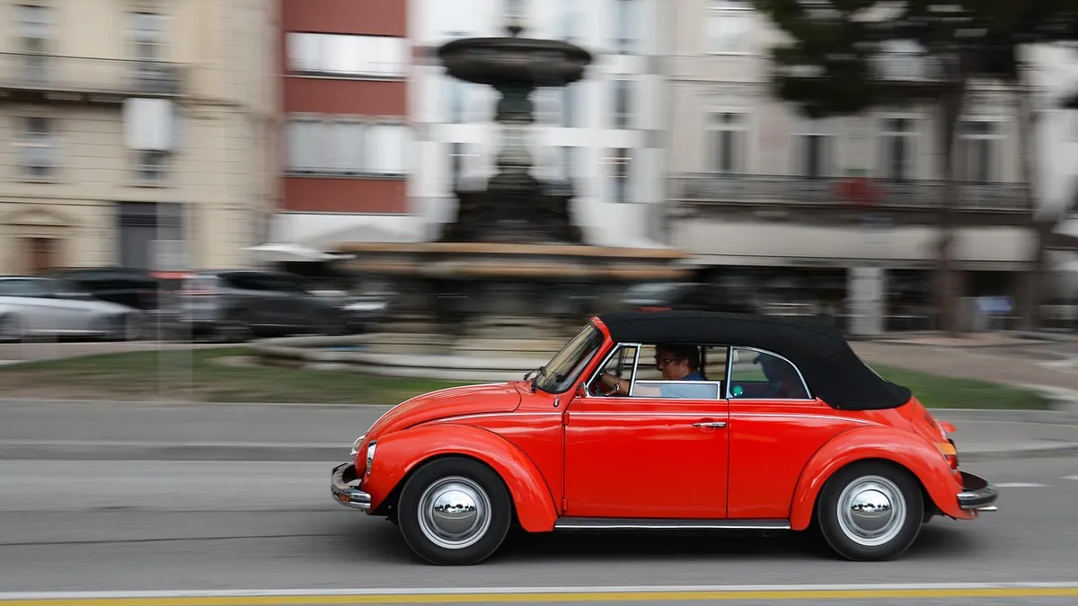 Carro conversível vermelho em avenida da cidade