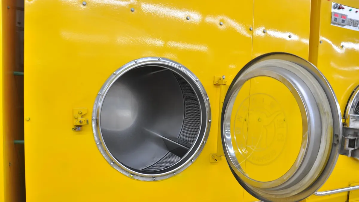Máquina de lavar industrial amarela com a porta aberta